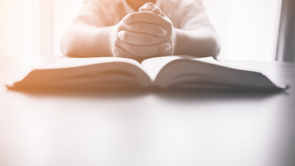shutterstock_627241544maos masculinas sobre Biblia iluminada em parte resto PB
