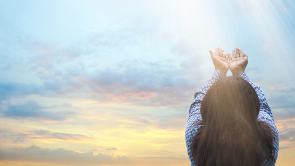 shutterstock_714648088mulher de costas com maos levantadas para o ceu ceu azul