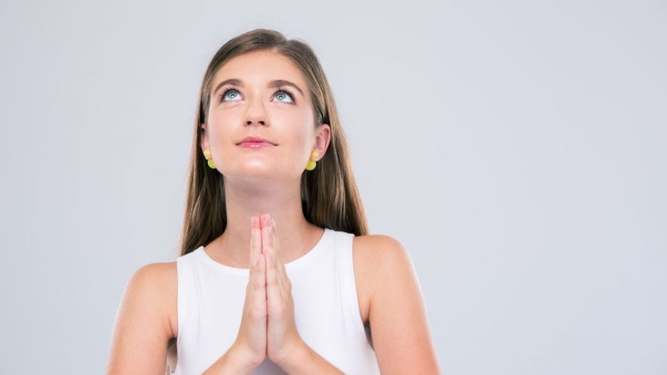 Portrait of attractive female teenager praying